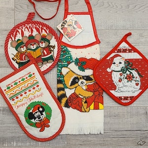 May include: Set of four red and white Christmas themed kitchen pot holders. One pot holder features a cat, another features a raccoon, and two feature mice. The pot holders have a white background with red trim and red polka dots. One pot holder has the text "Happy Holidays" on it.