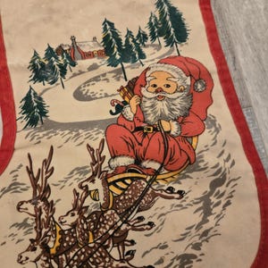 May include: Vintage Christmas stocking with a red and white Santa Claus riding in a sleigh pulled by reindeer. The stocking has a red trim and a white background with a winter scene.