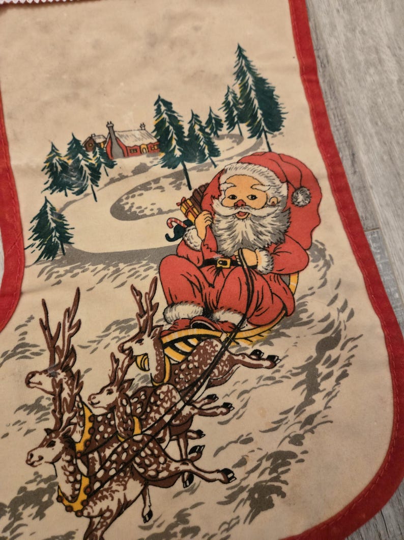 May include: Vintage Christmas stocking with a red and white Santa Claus riding in a sleigh pulled by reindeer. The stocking has a red trim and a white background with a winter scene.