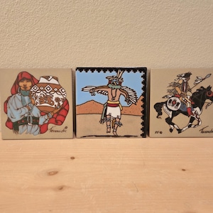 May include: Three square ceramic tiles with Native American-themed illustrations. One depicts a person holding a decorated pot, another a figure with outstretched arms, and the last a rider on horseback. Each tile has a unique design and color palette.