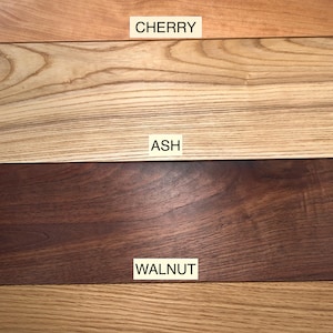 May include: Close-up of four different types of wood: cherry, ash, walnut, and white oak. Each wood sample is labeled with its name.