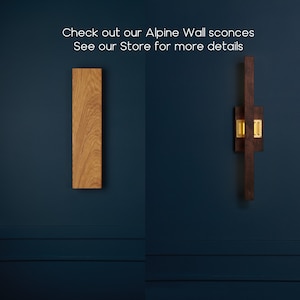 May include: Two wooden wall sconces, one with a natural wood finish and the other with a dark brown finish. Both sconces are rectangular in shape and feature a gold metal accent.