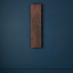 May include: A dark brown wooden rectangular sign with a wood grain pattern, mounted on a dark blue wall.