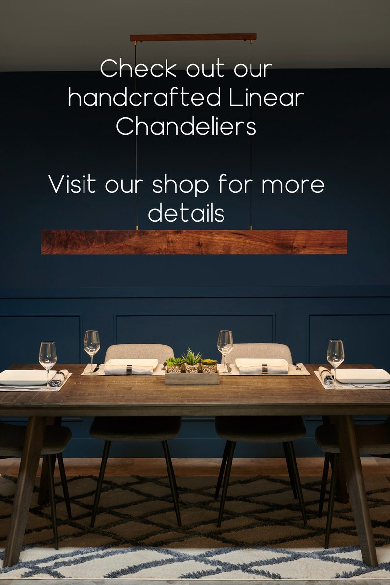 May include: A dark wood dining table with six chairs, set with place settings and a centrepiece of potted succulents. A wooden linear chandelier hangs above the table against a dark blue wall. The text "Check out our handcrafted Linear Chandeliers Visit our shop for more details" is displayed above the chandelier.