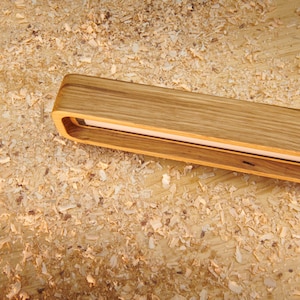 May include: A wooden light fixture with a rectangular shape and a white light source. The fixture is made of natural wood with a light brown color and a smooth finish. The light source is visible through a rectangular opening in the fixture.