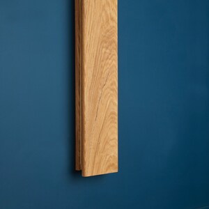 May include: A wooden wall sconce with a natural wood finish. The sconce is mounted on a blue wall.