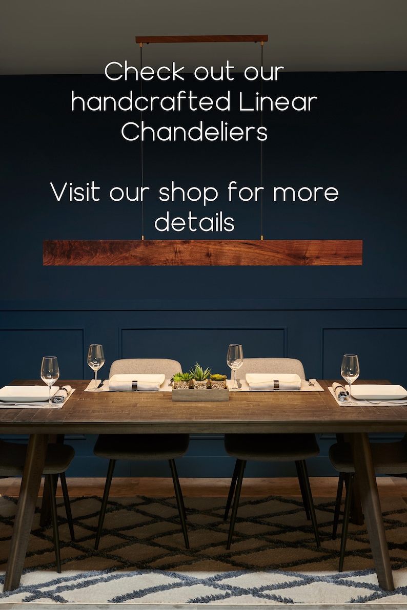 May include: A dark wood dining table with six chairs, set with place settings and a centerpiece of potted succulents. A wooden linear chandelier hangs above the table against a dark blue wall. The text "Check out our handcrafted Linear Chandeliers Visit our shop for more details" is displayed above the chandelier.