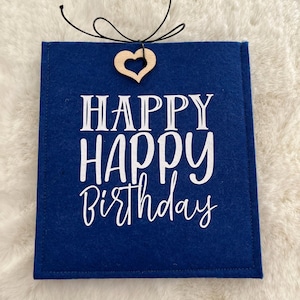 Peut inclure: Un sac cadeau rectangulaire en feutrine bleu foncé avec le texte blanc "HAPPY HAPPY BIRTHDAY" imprimé sur le devant. Un petit cœur en bois clair est attaché au centre supérieur avec une fine ficelle noire nouée en un nœud décoratif.