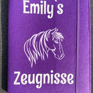 Könnte beinhalten: Lilafarbener Filzordner mit einer weißen Pferdesilhouette und dem Text "Emily's Zeugnisse".