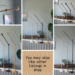 May include: A set of wooden baby mobile arms in various colors, including black, white, gold, and natural wood. The arms are designed to be mounted on a railing or wall and feature a swiveling arm with a wooden ball at the end. The arms are 40cm (15.7 inches) long.