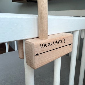 May include: A wooden crib with a wooden bar attached to the side. The bar is 10cm (4in) long and is attached to the crib with a wooden bracket.