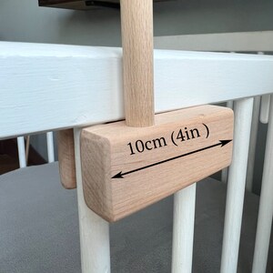 May include: A wooden crib with a wooden bar attached to the side. The bar is 10cm (4in) long and is attached to the crib with a wooden bracket.