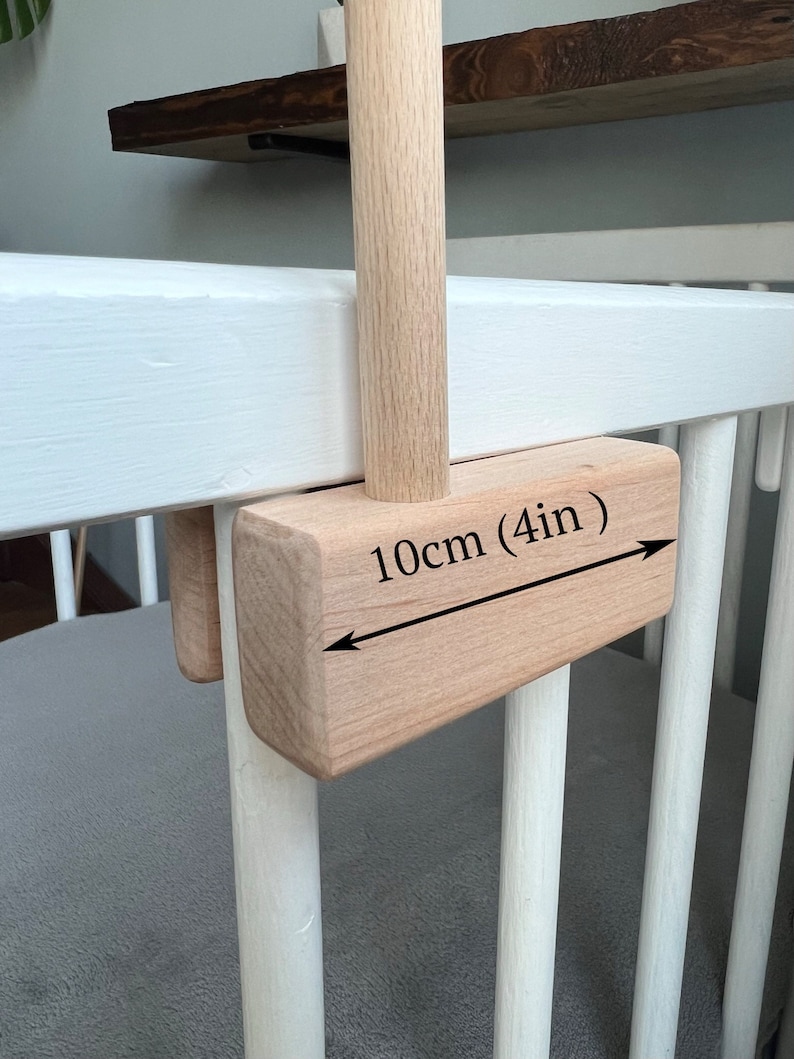 May include: A wooden crib with a wooden bar attached to the side. The bar is 10cm (4in) long and is attached to the crib with a wooden bracket.