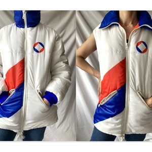 May include: White puffer jacket and vest with red, blue, and white color blocking. The jacket has a zipper closure and a logo with a circle and a square inside. The vest is sleeveless.