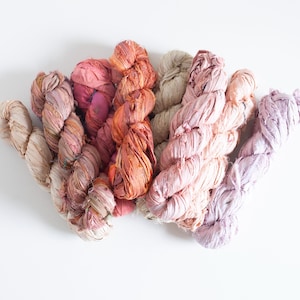 Puede incluir: Surtido de seis ovillos de hilo de cinta de seda teñido a mano en tonos de rosa, melocotón y naranja. El hilo está hecho de seda reciclada y es perfecto para tejer o hacer ganchillo.