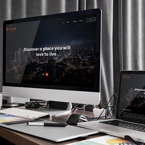 Puede incluir: Un escritorio con un ordenador de sobremesa y un port&aacute;til que muestran un sitio web con el texto "Discover a place you will love to live." Tambi&eacute;n se ven un teclado, un rat&oacute;n y una tableta gr&aacute;fica.