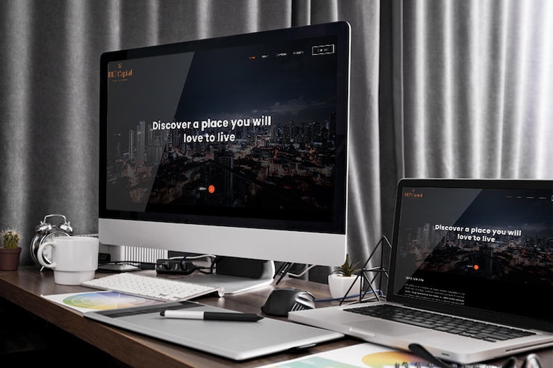 Puede incluir: Un escritorio con un ordenador de sobremesa y un port&aacute;til que muestran un sitio web con el texto "Discover a place you will love to live." Tambi&eacute;n se ven un teclado, un rat&oacute;n y una tableta gr&aacute;fica.