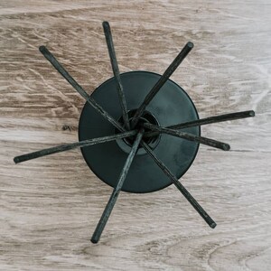 May include: Black diffuser sticks radiating out from a black ceramic base on a wood surface.