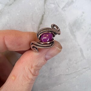 May include: A copper wire wrapped ring with a purple gemstone in the center.