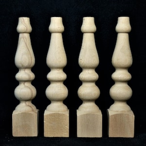 May include: Four unfinished wooden table legs with a bulbous design. Each leg has a square base.