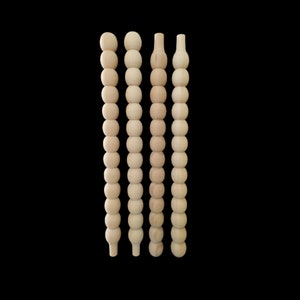 Può includere: Quattro pioli di legno con una fila di perline di legno. I pioli sono di diverse lunghezze e le perline sono tutte della stessa dimensione.