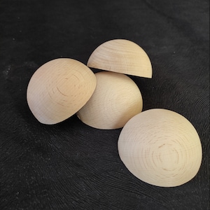 Könnte beinhalten: Vier unfertige, halbrunde Holzformen, die auf einer schwarzen Oberfläche gestapelt sind.