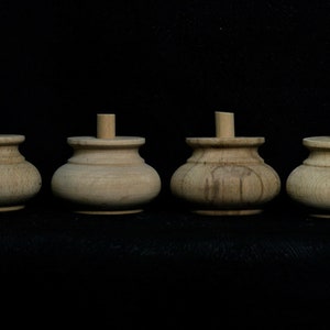 May include: Four wooden furniture legs with a rounded top and a slightly flared base. The legs are unfinished and have a natural wood color.