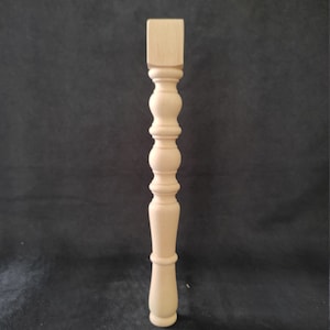 K&ouml;nnte beinhalten: Ein Tischbein aus Holz mit quadratischer Oberseite und gedrehtem Design. Das Bein ist unbehandelt und kann gebeizt oder lackiert werden.
