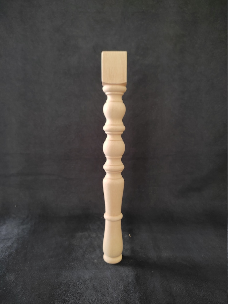 K&ouml;nnte beinhalten: Ein Tischbein aus Holz mit quadratischer Oberseite und gedrehtem Design. Das Bein ist unbehandelt und kann gebeizt oder lackiert werden.