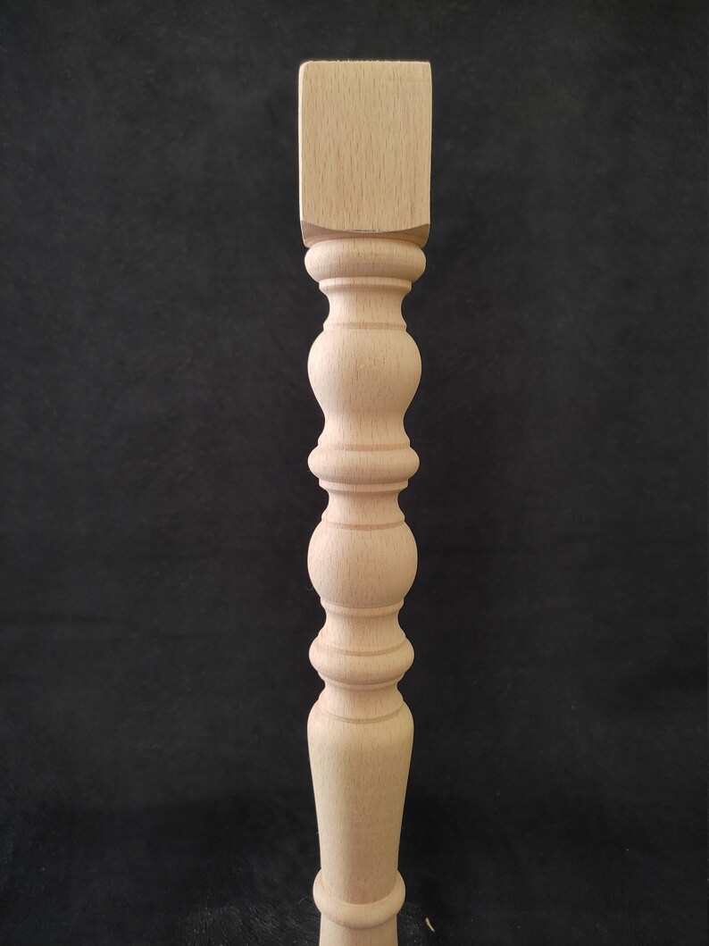 K&ouml;nnte beinhalten: Ein Tischbein aus Holz mit quadratischer Oberseite und gedrehtem, geriffeltem Design. Das Bein ist unbehandelt und hat eine nat&uuml;rliche Holzfarbe.