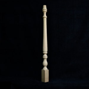 May include: A wooden spindle with a turned design and a square base. The spindle is light brown in color and has a smooth finish.