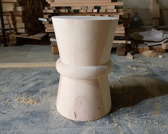 May include: A light wood stool with a rounded top and a wide base. The stool is made of unfinished wood and has a natural wood grain.