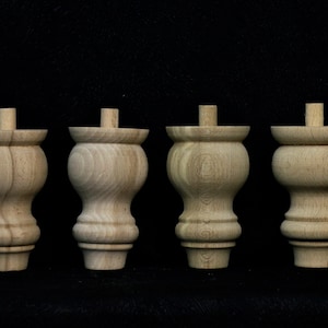 Peut inclure: Quatre pieds de meubles en bois avec un design tourné. Les pieds sont non finis et ont une couleur bois naturelle.