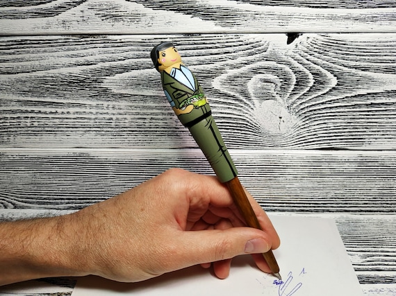 A wooden ballpoint pen shaped like a fishing rod — a tiny handcrafted novelty that doubles as a genuinely functional desk item.