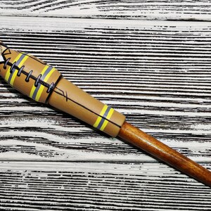 May include: A wooden pen with a brown and yellow painted design of a firefighter. The pen has a brown wooden barrel and a black ink tip.