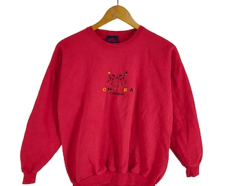 May include: Red long-sleeve sweatshirt with a colorful embroidered logo that says "Montreal Canada" and features two cartoon figures.