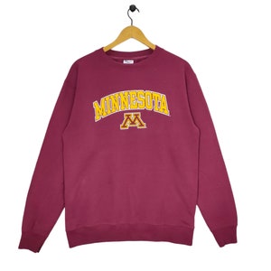 May include: Burgundy sweatshirt with a yellow and gold "Minnesota" arch with a yellow and gold "M" inside the arch.