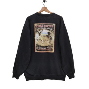 May include: Black sweatshirt with a vintage-style graphic print of a whitetail deer. The print features the text "Field Tested Outdoor Gear" and "19 Whitetail Deer 20 North America's Northwest".