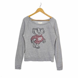 May include: Gray sweatshirt with a vintage-style graphic of the Wisconsin Badgers mascot, a badger wearing a red and white striped sweater with a "W" on it.