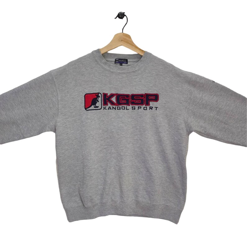 May include: Gray sweatshirt with a red and blue kangaroo logo and the text "KGSP KANGOL SPORT".