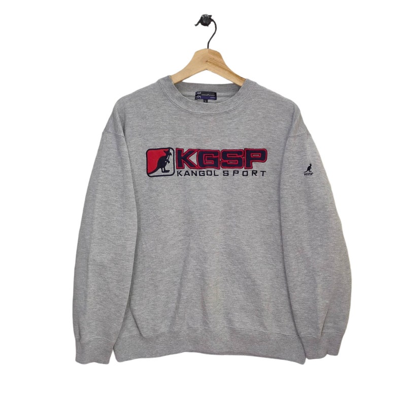 May include: A gray sweatshirt with a red and blue kangaroo logo that says "KGSP KANGOL SPORT".