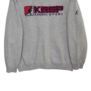 May include: Gray sweatshirt with a red and blue kangaroo logo and the text "KGSP KANGOL SPORT".