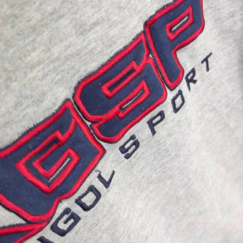 May include: A gray sweatshirt with the text "GOLF SPORT" embroidered in blue and red.