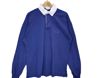 May include: A blue long-sleeve rugby shirt with a white collar and a small embroidered logo that says "FLAMINGO 204".