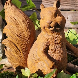 Peut inclure: Une figurine d'écureuil marron texturée avec une grande queue touffue et des détails de fourrure marqués. L'écureuil est représenté en position assise, la bouche légèrement ouverte, offrant un aspect réaliste avec une finition mate et terreuse.