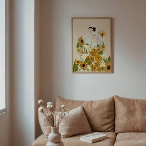 May include: A framed illustration of a woman wearing a dress made of sunflowers. The woman is sitting with her legs crossed and her hands in her lap. The background is a light beige color.