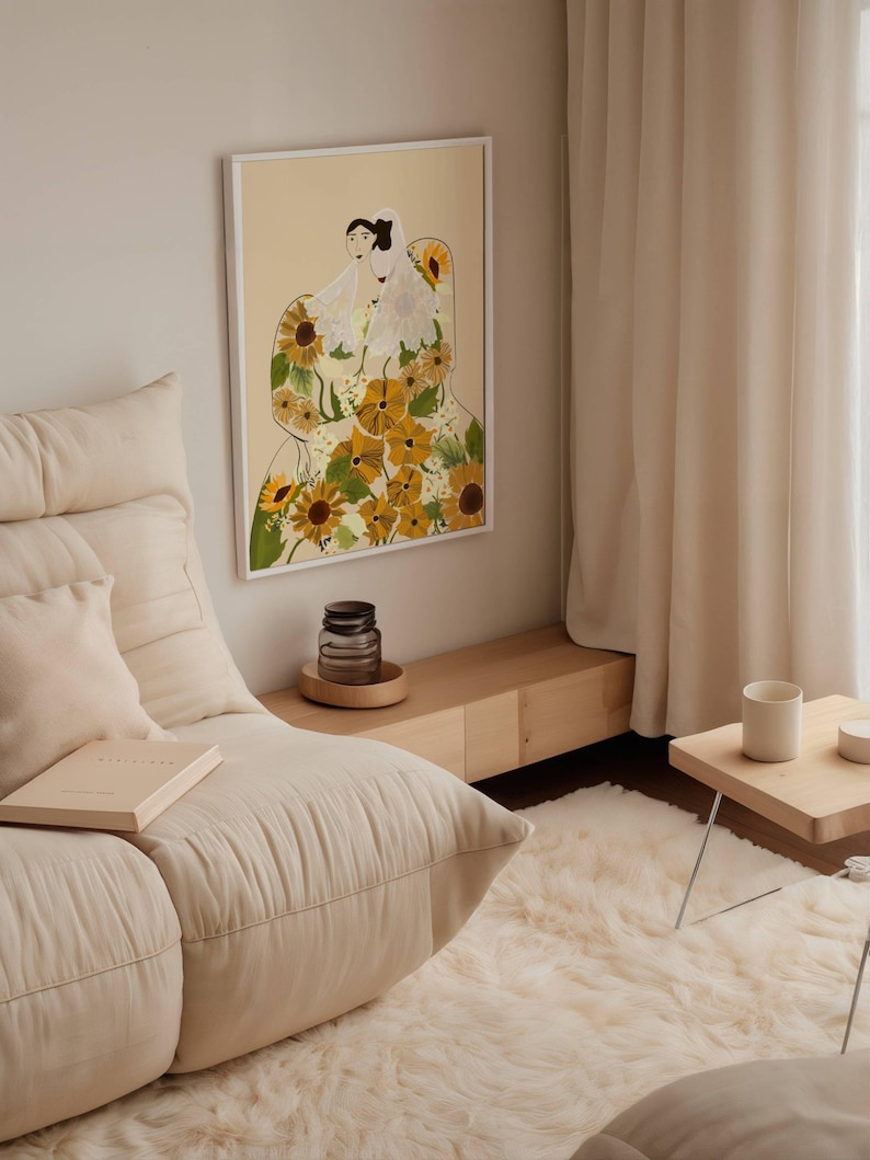 May include: A framed illustration of two women wearing white dresses with a floral pattern of yellow sunflowers. The background is a light peach color.