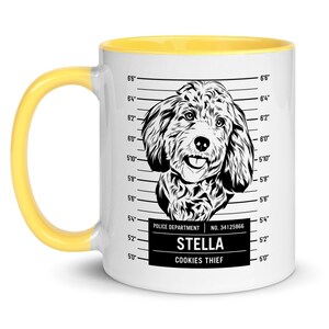 May include: White ceramic mug with a yellow rim. The mug features a black and white illustration of a dog with the text "STELLA COOKIES THIEF" and "POLICE DEPARTMENT NO. 34125866" below the dog.