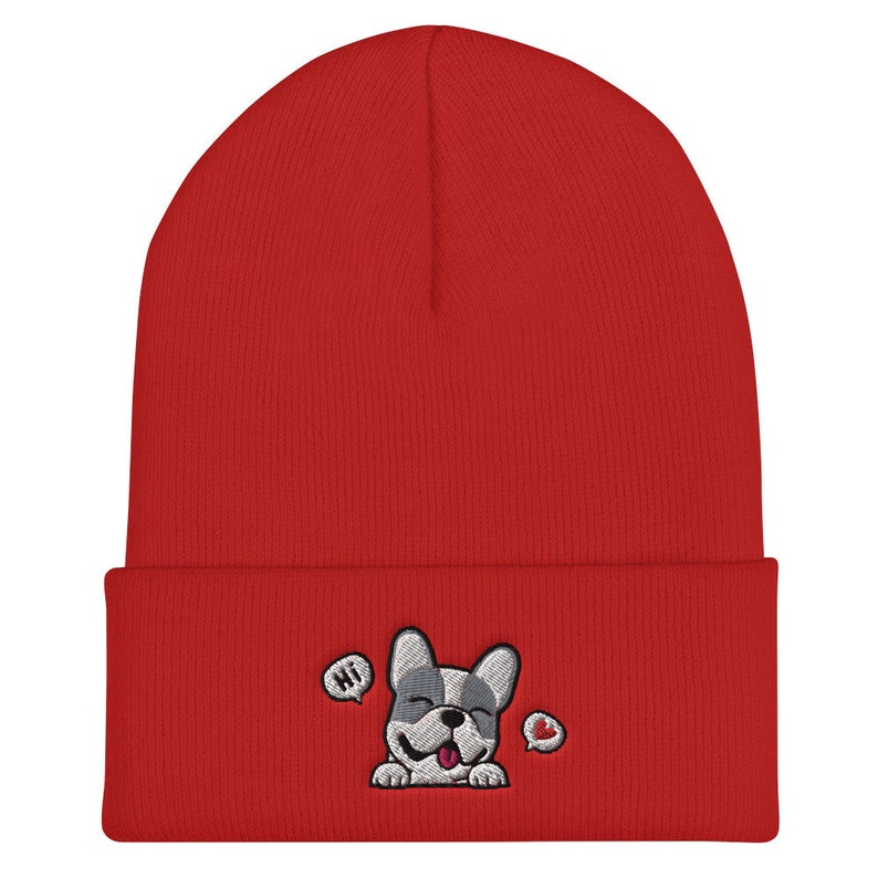 Puede incluir: Gorro de punto rojo con un bulldog franc&eacute;s bordado en blanco y gris con una burbuja de di&aacute;logo que dice "Hola" y un coraz&oacute;n.
