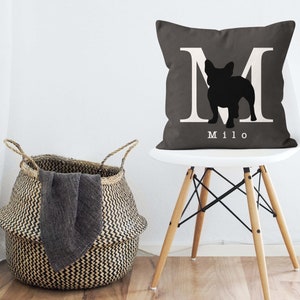 May include: A gray throw pillow with a white letter M and a black silhouette of a French bulldog. The pillow has the name "Milo" printed in white below the silhouette.